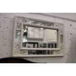 A decorative wall mirror with white painted frame.