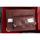 A Cartier burgundy leather ladies' purse / wallet together with a similar address book and cover.