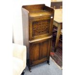 A narrow oak cupboard with drop flap and rising compartment.