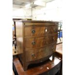 A reproduction mahogany bow front chest with brushing slide and three long drawers on bracket feet.