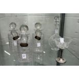 A set of three cut glass decanters with silver decanter labels together with another decanter and