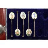 A part cased set of five silver and floral enamelled backed coffee spoons.