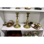 A pair of brass candlesticks with later electric light fittings.
