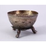 A SMALL THAI EMBOSSED SILVER BOWL, on three feet, 6cm wide.