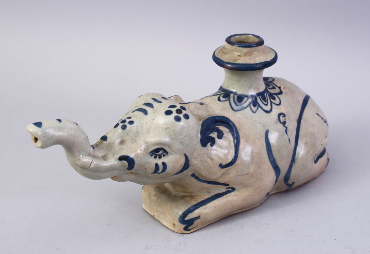 AN UNUSUAL 19TH CENTURY INDIAN POTTERY HUQQA BASE, in the form of a recumbent elephant, 28cm long.