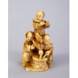 A JAPANESE MEIJI PERIOD CARVED IVORY NETSUKE OF THREE BOYS, the three boys stood each playing an