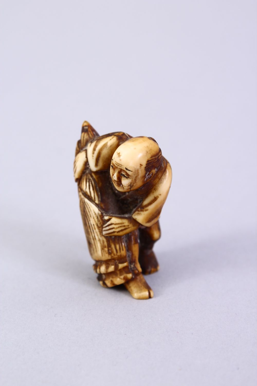 A JAPANESE MEIJI PERIOD CARVED IVORY NETSUKE, the figure holding a tied parcel, signed to side, 3. - Image 5 of 6