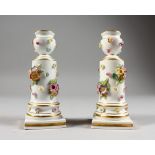 A SMALL PAIR OF MEISSEN PORCELAIN FLOWER ENCRUSTED CANDLESTICKS, on square bases. Cross swords