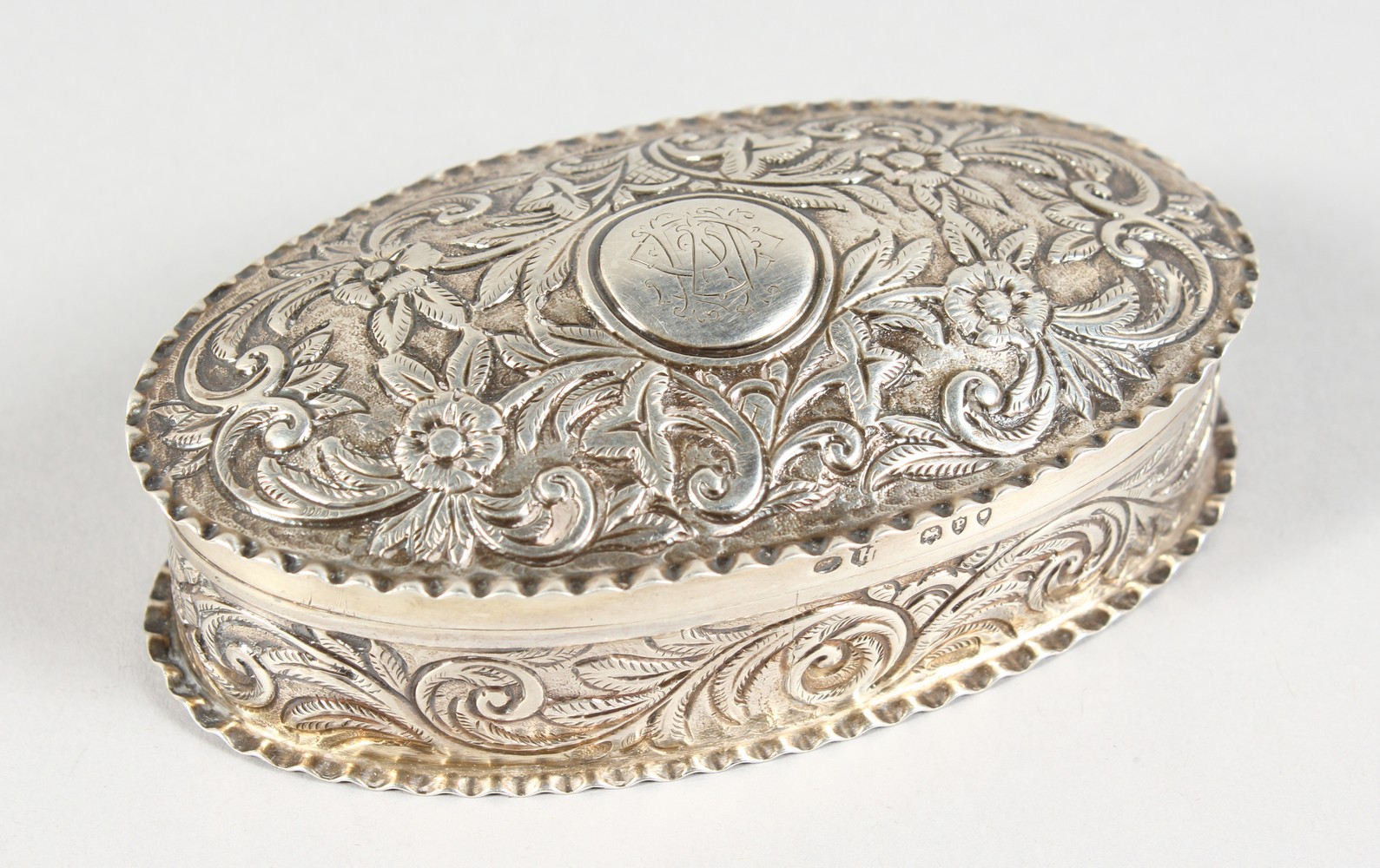 A VICTORIAN OVAL SILVER PIN BOX AND COVER, with repousse decoration. London 1890.