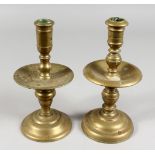 TWO 19TH CENTURY BRASS CIRCULAR CANDLESTICKS, possibly Continental, with broad drip pans. 8.5ins