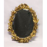 AN 18TH / 19TH CENTURY GILT FRAMED OVAL MIRROR, with well carved leaf and berry frame and ribbon and