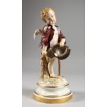 A MEISSEN PORCELAIN FIGURE OF A CHERUB holding a hat and walking with a stick. Cross swords mark