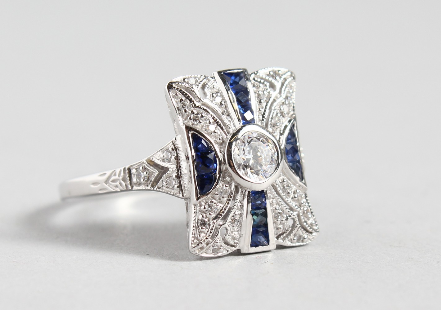 A SILVER DECO DESIGN FAUX SAPPHIRE RING.