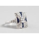 A SILVER DECO DESIGN FAUX SAPPHIRE RING.