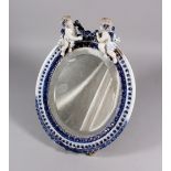 A DRESDEN PORCELAIN OVAL MIRROR, with two cupids and garlands. 14ins high.