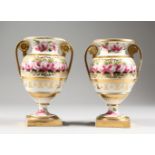 A PAIR OF TWO-HANDLED URN SHAPED VASES, with gilt decoration painted with roses. 7ins high.