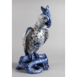 A LARGE POTTERY FIGURE OF A PARROT ON A TREE STUMP, with blue floral painted body. 16ins high.