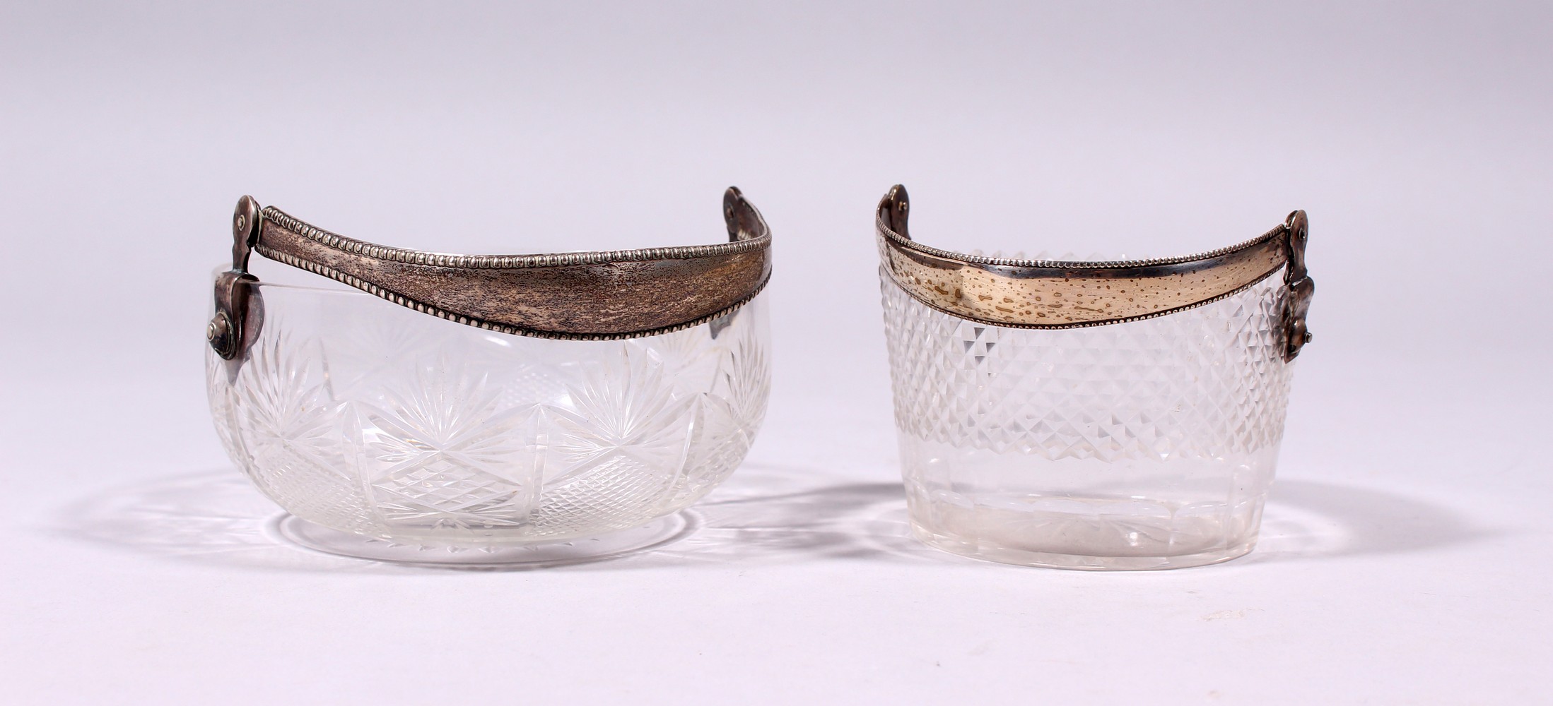 TWO CONTINENTAL CUT GLASS CIRCULAR BASKETS, with silver swing handles.