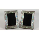 A PAIR OF ART NOUVEAU STYLE SILVER AND ENAMEL PHOTO FRAMES. 7.5ins high x 5.75ins.