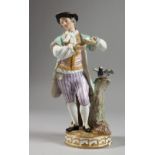 A MEISSEN PORCELAIN FIGURE OF A YOUNG MAN standing beside a tree stump with a bird. Cross swords