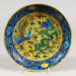 A CHINESE PORCELAIN CIRCULAR DISH, painted in green, yellow and blue, with incised dragons. 9ins