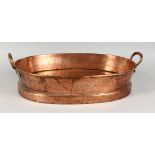 A 19TH CENTURY OVAL COPPER TWIN-HANDLED PAN, on a raised foot. 22ins long.