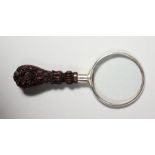 A SMALL MAGNIFYING GLASS with carved handle.