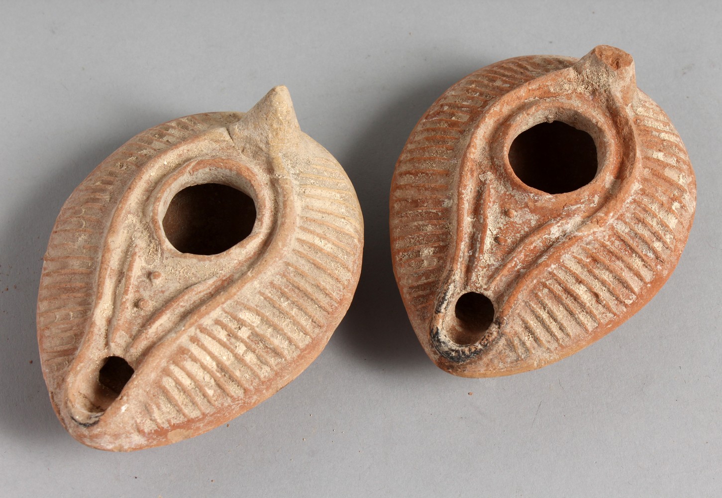 TWO SMALL TERRACOTTA OIL LAMPS.