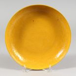 A CHINESE PORCELAIN CIRCULAR DISH, yellow ground with dragon decoration. 9ins diameter.