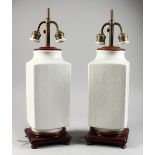 A PAIR OF WHITE PORCELAIN AND HARDWOOD CHINESE TABLE LAMPS, with moulded calligraphy design, and