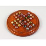 A WOODEN SOLITAIRE BOARD WITH AIR TWIST MARBLES. 8.5ins diameter.