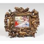 A CLASSICAL PORCELAIN PLAQUE, 2.25ins x 3.75ins, in a cased bronze frame with cupids and trophies.