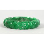 A CHINESE CARVED APPLE GREEN JADE BANGLE. 3ins diameter.