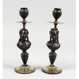 A PAIR OF BRONZE AND METAL CANDLESTICKS, depicting a bust of a lady, on circular bases. 10ins high.