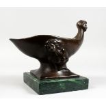 AN UNUSUAL ART DECO DESIGN BRONZE CUP, with mask handle, on a marble base. 12ins long.
