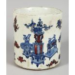 A CHINESE PORCEAIN BRUSH POT, painted in blue and red, with vases and other emblems. 7ins high.
