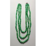 A GOOD JADE THREE-ROW NECKLACE, with diamond and ruby set clasp.