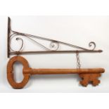 AN UNUSUAL FOLK ART/SHOP SIGN, modelled as a carved and painted wood key, suspended from a wrought