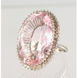 A VERY LARGE PINK OVAL STONE, surrounded by diamonds, set in white gold.