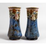 A PAIR OF ROYAL DOULTON POTTERY VASES, blue glazed with moulded fruit and vine decoration. 8ins