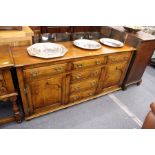 A good reproduction oak dresser with four drawers flanked by further drawers and cupboards doors