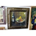 Still life of fruit in a bowl next to a bottle of oil signed in a decorative frame