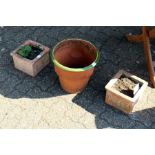 A pair of small terracotta planters and a terracotta plant pot