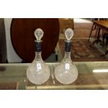 A pair of cut glass decanters with silver collars