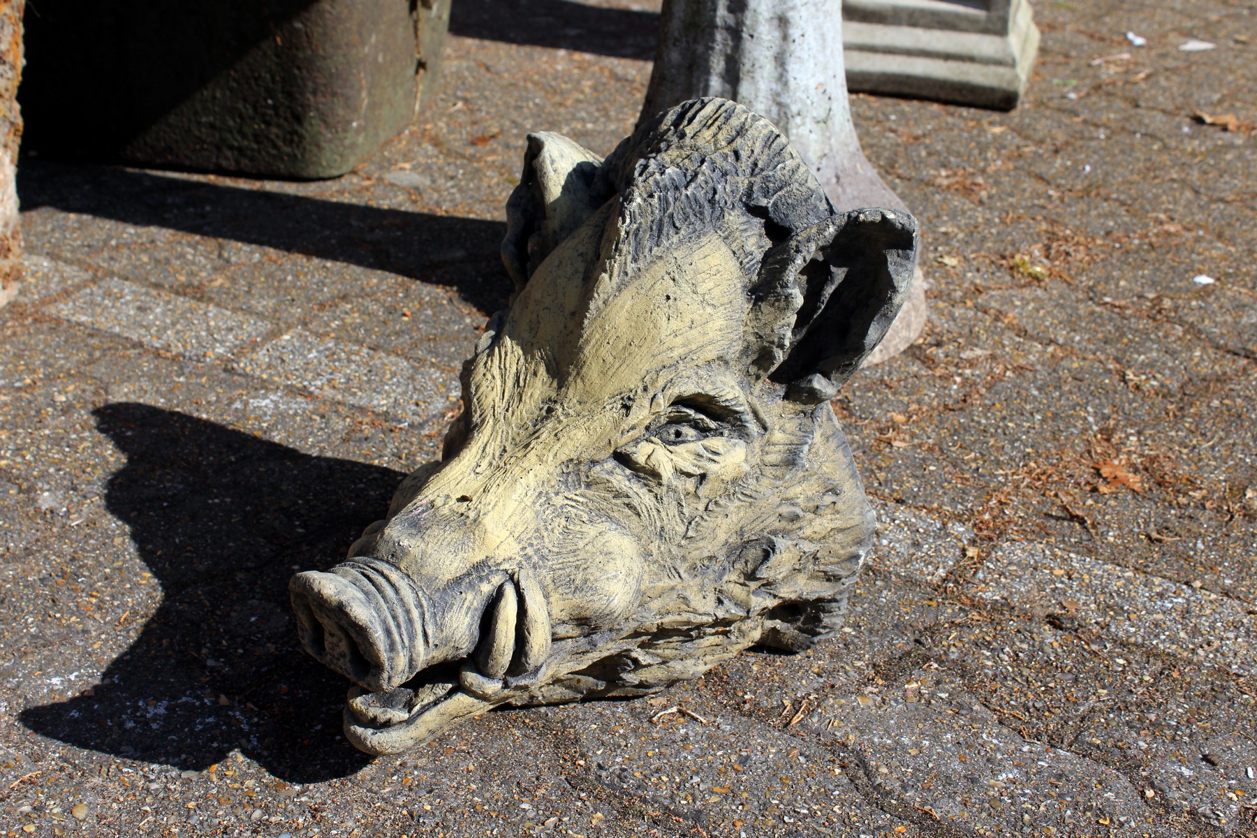 A reconstituted stone boars head garden ornament