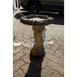 A reconstituted stone bird bath modelled as three cherubs