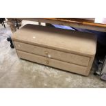 An upholstered two drawer ottomen