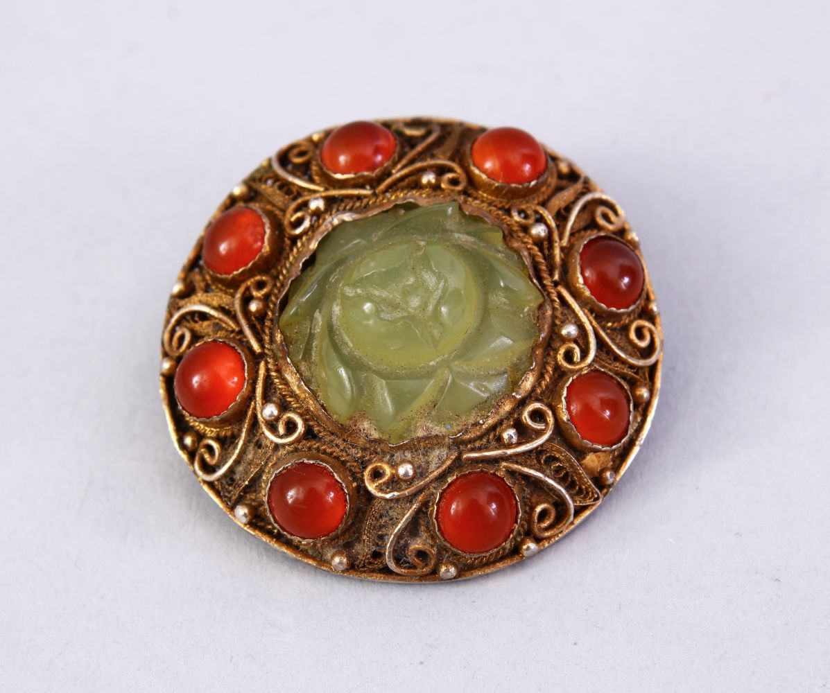 A GOOD INDIAN SILVER GILT & JADE BROOCH, with filigree work enclosing a floral carved jade centre,