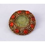 A GOOD INDIAN SILVER GILT & JADE BROOCH, with filigree work enclosing a floral carved jade centre,