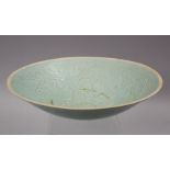 A CHINESE SONG STYLE CELADON POTTERY CARVED BOWL, the bowl carved with floral decoration, the base